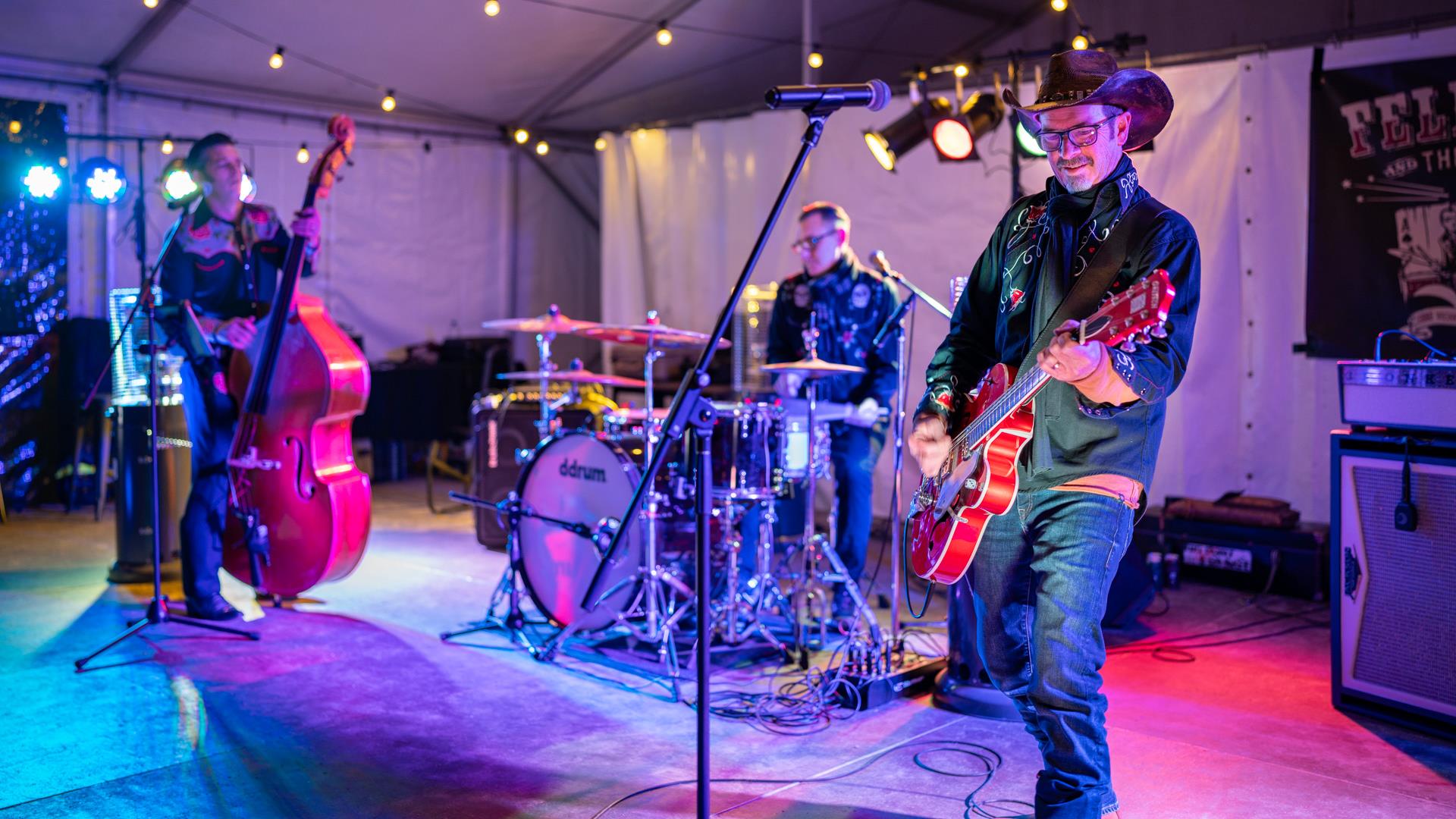 Band playing on stage under colourful lights at night.